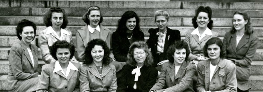 The first class of women admitted to Harvard Medical School sitting together on the steps of Gordon Hall in 1945.